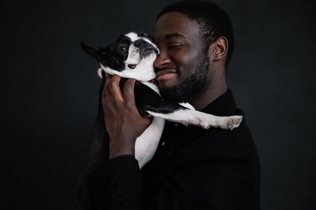 black man hugging dog near black wall