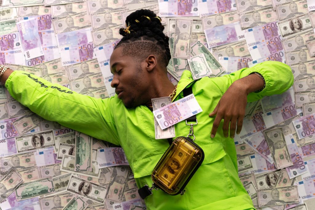 man in green jacket lying down on money